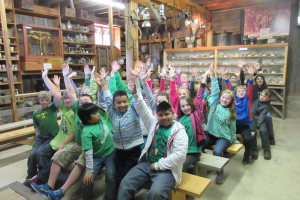 A group of smiling school children with hands raised