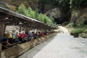 A mining flume with people hunting for gems and a historic mine in the background